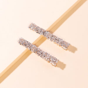 A pair of silver and white diamond hairpins with gold bottom