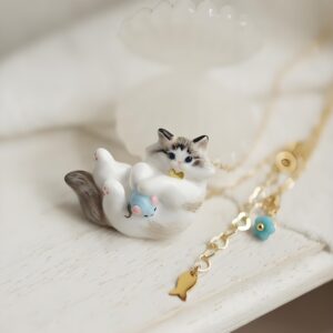 Gray cat holding blue toy gold bow tie necklace